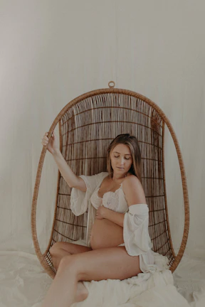 A serene mother-to-be sitting comfortably in a softly lit room, supported by her doula.