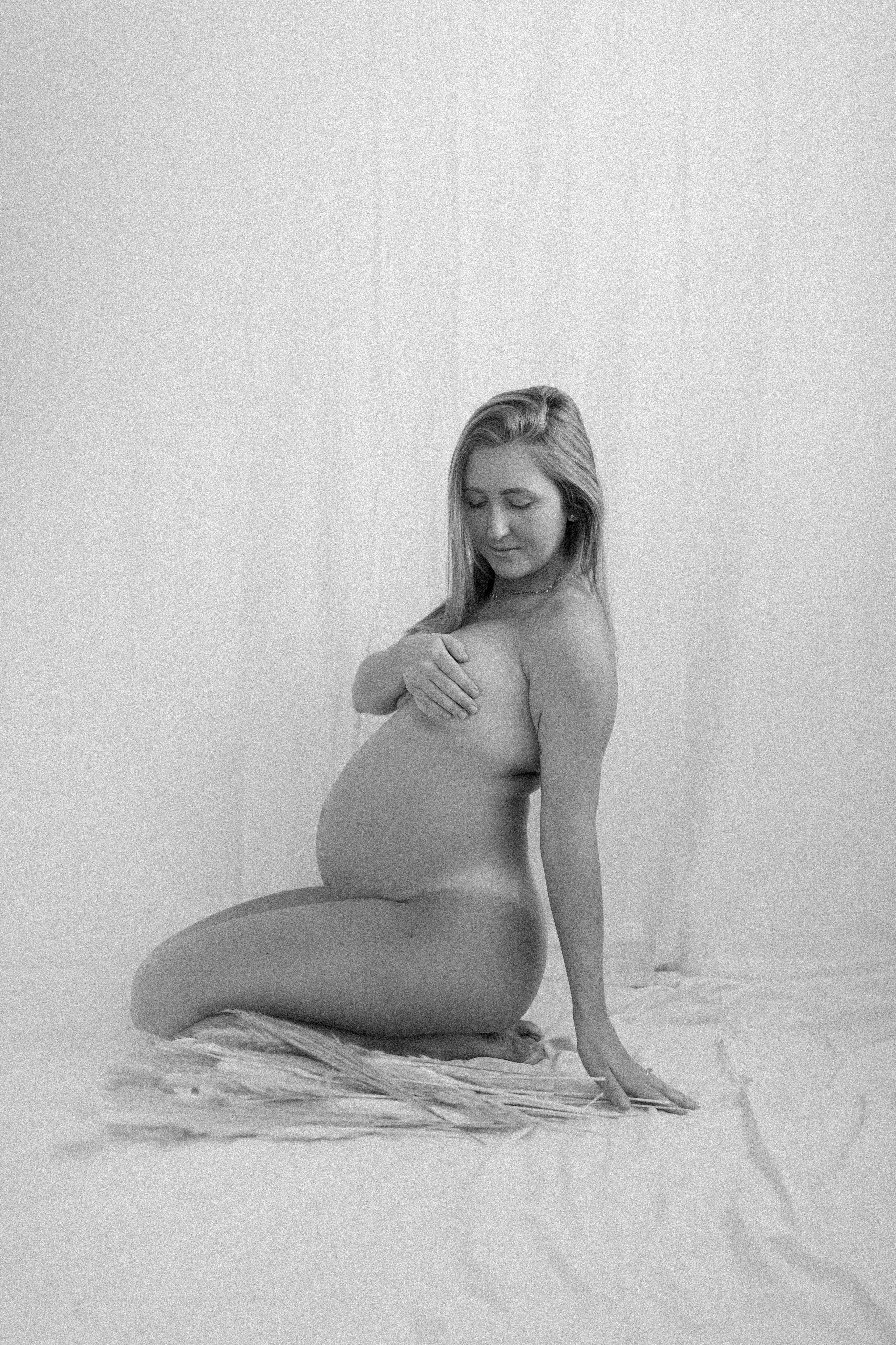 A pregnant woman sitting on a bed in a black and white photo photo