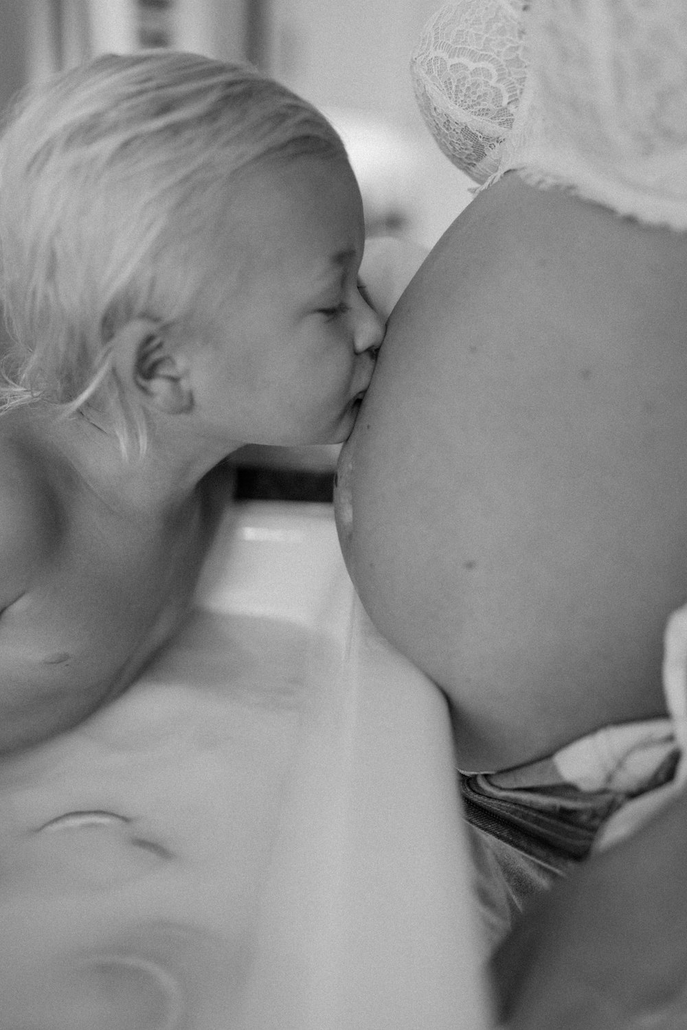 a black and white photo of a woman kissing a baby