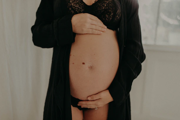 A pregnant woman gently holding her belly inside a car seat, highlighting safety.