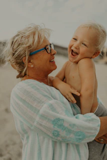 A joyful senior woman using a sleek Vidaluz device while laughing with her grandchild in a sunny park.