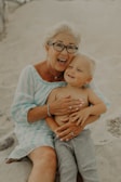 An elderly woman smiling while holding a child's hand.