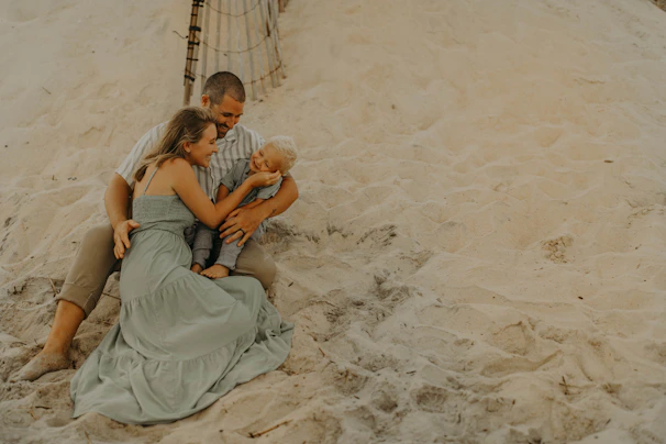 Sun-drenched family sharing an intimate hug on a soft sandy beach with charcoal text overlay.