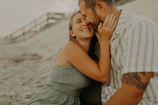 An intimate moment between partners captured candidly with a soft sand backdrop.