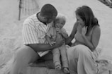 A family enjoying a day at the beach, playing in the sand and surf.