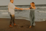 A candid photo of a smiling couple holding hands in golden sunlight, surrounded by soft sand tones.