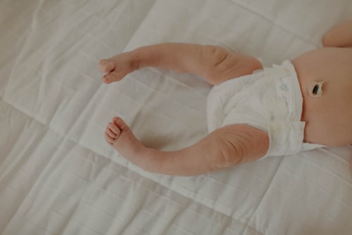 A baby lying on a bed wearing a diaper