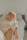 A peaceful, sleeping baby is gently cradled in someone's arms, wearing a soft, knitted cream sweater. The lighting is warm and soft, creating a serene and intimate atmosphere. In the background, a blurred bed adds a sense of calm domesticity.