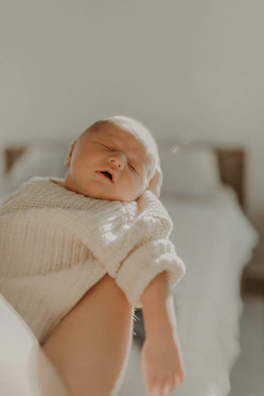 A serene beachside villa where a babysitter gently holds a newborn wrapped in a soft beige blanket.