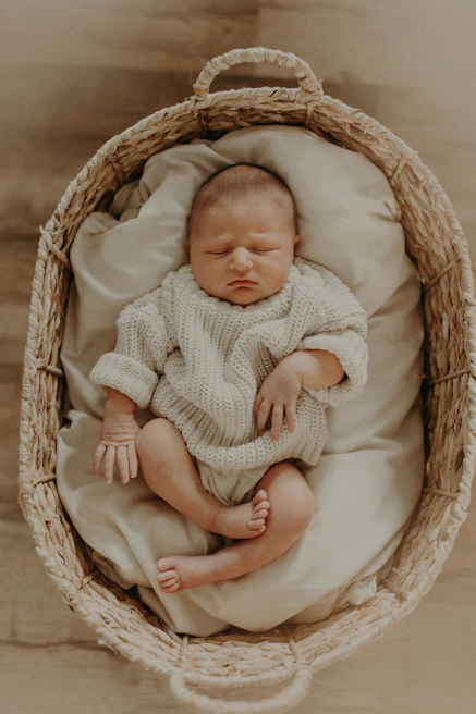 A newborn wrapped in a soft cream blanket, peacefully sleeping in a basket