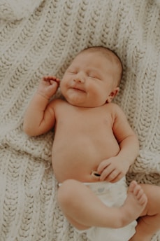 A happy baby wearing a soft, snug nappy sitting on a cozy blanket