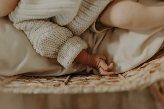 A cozy corner with a beige knitted blanket and soft baby clothes.