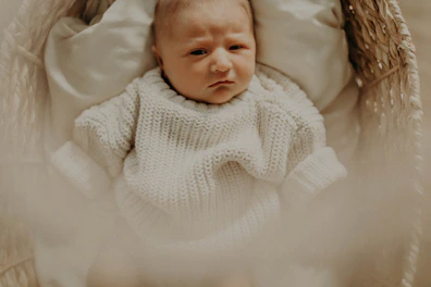 Tiny baby clothes in gentle colors displayed on a cozy knitted blanket.