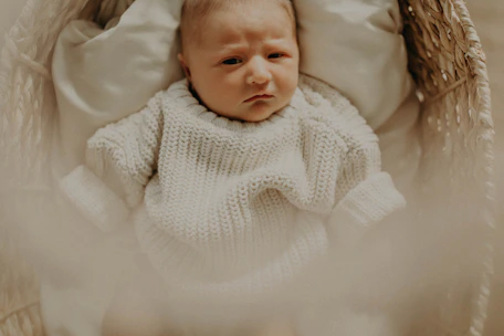Soft pastel-colored baby clothes neatly arranged on a wooden surface with gentle natural light