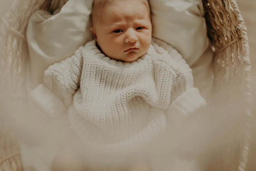 Cozy baby wrapped in a soft onesie, surrounded by plush toys and nursery accessories in a warm boutique setting