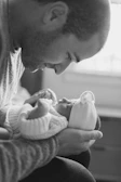 A tender scene of newborn gifts arranged softly on a white linen cloth.
