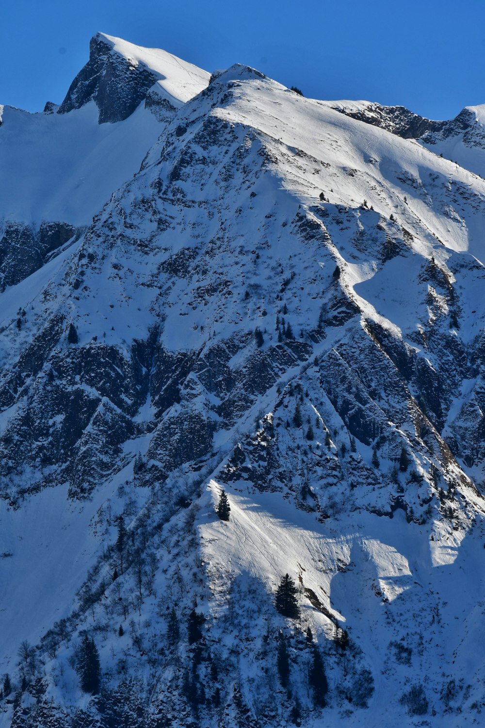 a mountain covered in snow with a blue sky in the background