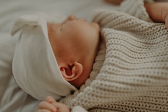 Close-up of a newborn wearing a delicate cotton hat with tiny ears.