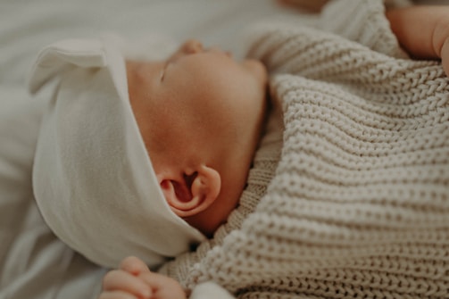 Close-up of a delicate crochet baby cap in soft pastel colors.