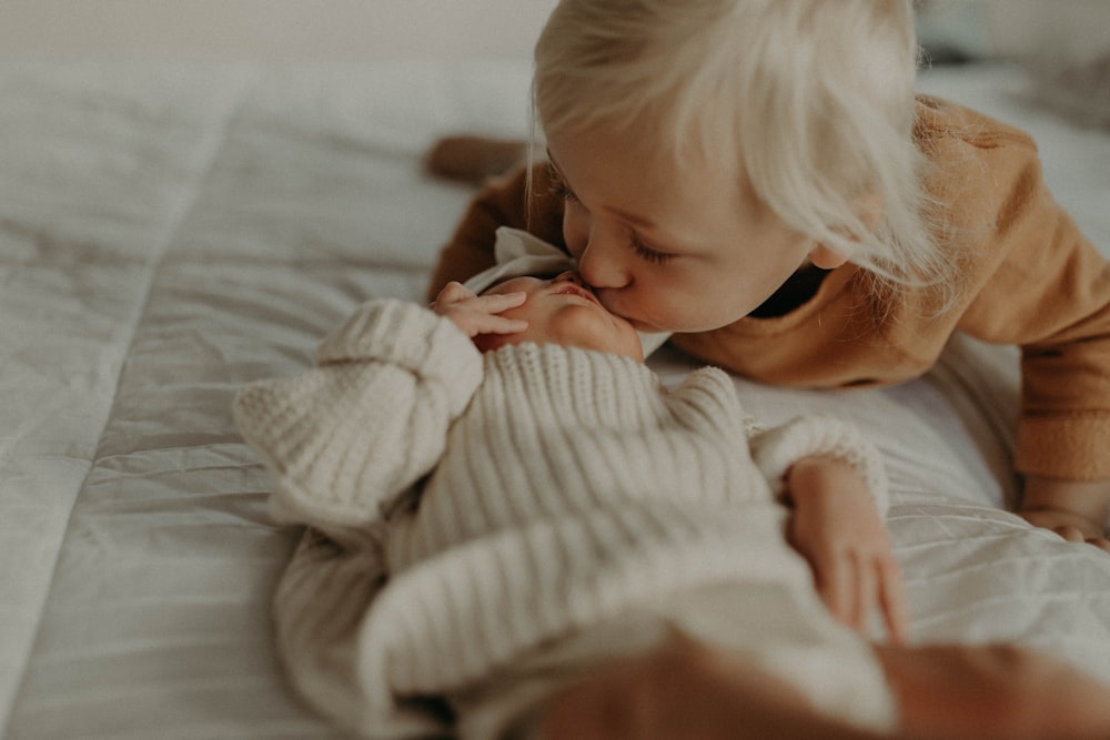 a little girl laying on top of a bed next to a stuffed animal