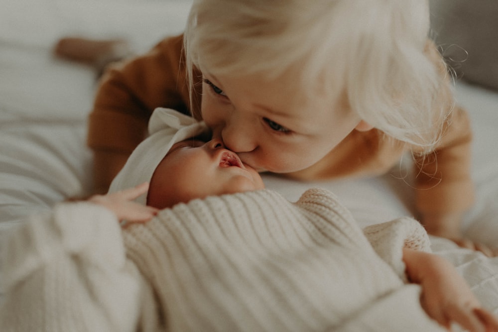 a little girl kissing a baby on the cheek