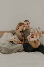 a man and a woman are sitting on a bed with a baby