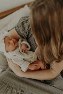 A calm mother softly rocking her peacefully sleeping baby in a cozy nursery.