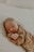 A sleeping baby rests peacefully on a soft surface, dressed in cozy, ribbed fabric. The gentle lighting enhances a serene and tender atmosphere.