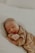 A sleeping baby rests peacefully on a soft surface, dressed in cozy, ribbed fabric. The gentle lighting enhances a serene and tender atmosphere.
