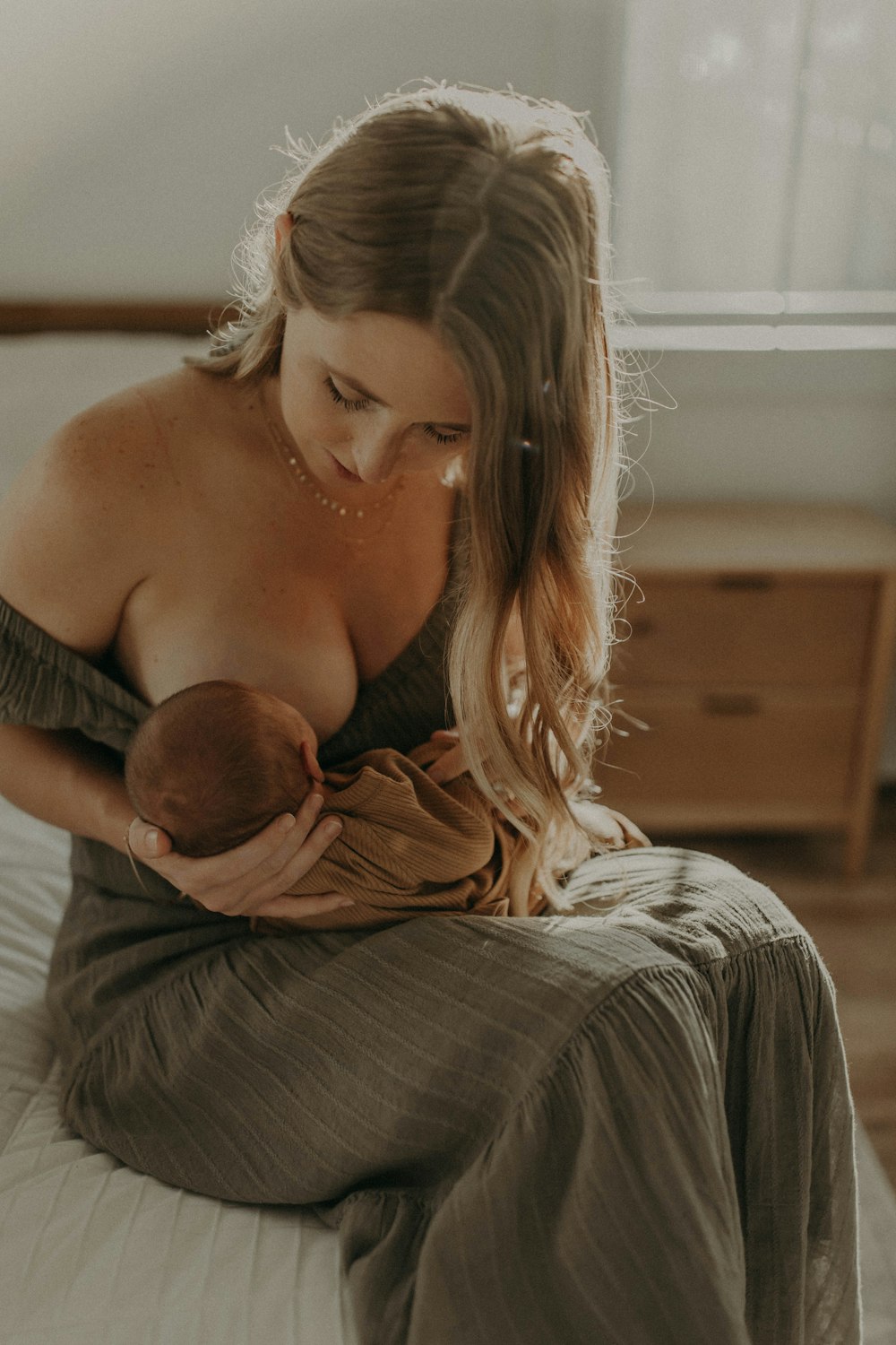 a woman holding a baby while sitting on a bed