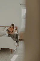 A serene moment of a mother meditating with her child nearby in a calm, minimalist room.