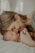A tender moment between a mother and her sleeping baby, as they gently touch foreheads while the mother holds the baby's hand. The mood is serene and intimate, with soft lighting enhancing the sense of warmth and closeness.