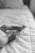 A black and white photograph of a baby lying on a soft, quilted surface. The focus is on the small feet and toes of the infant, which adds a delicate and tender quality to the image.