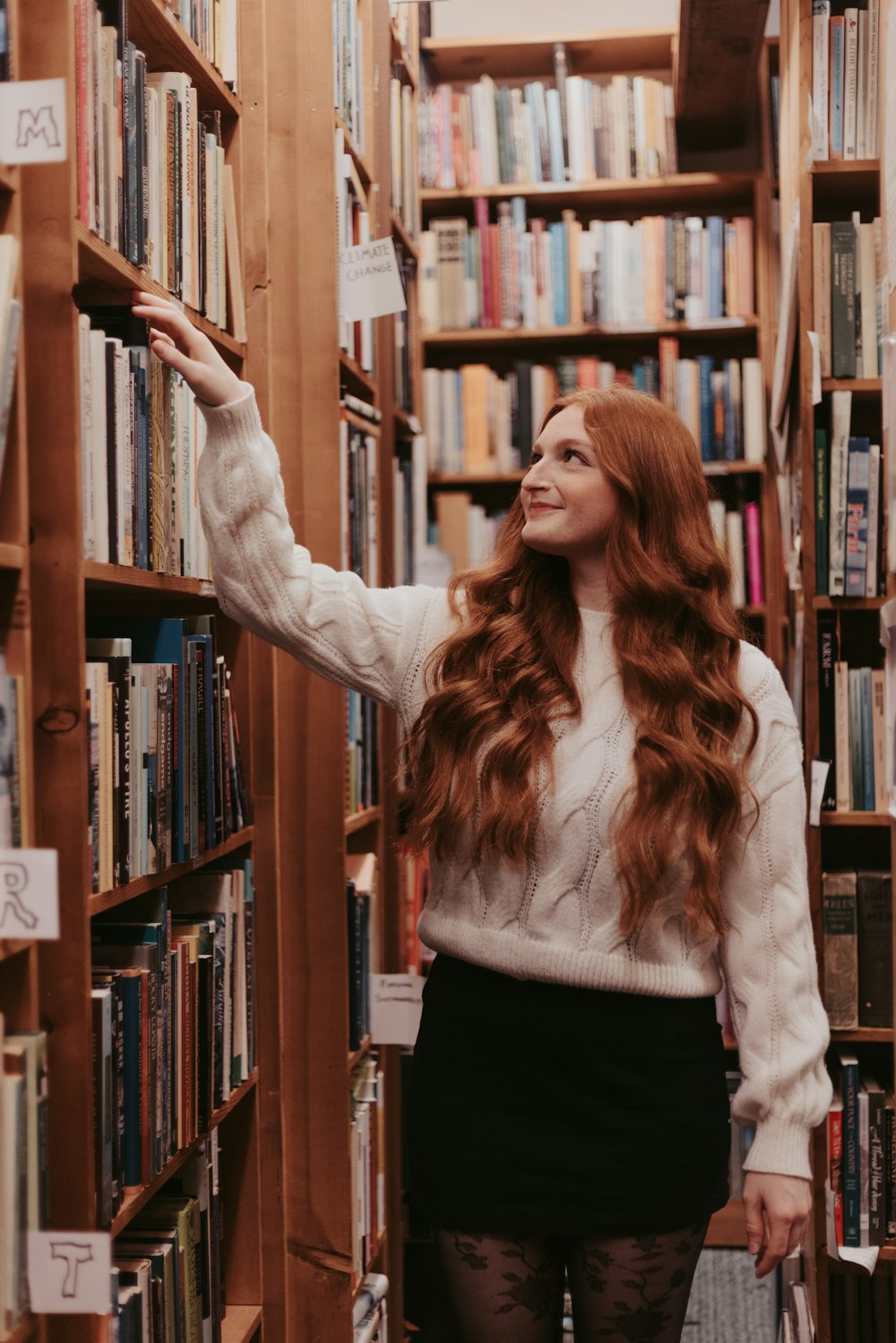 a woman standing in front of a book shelf filled with books