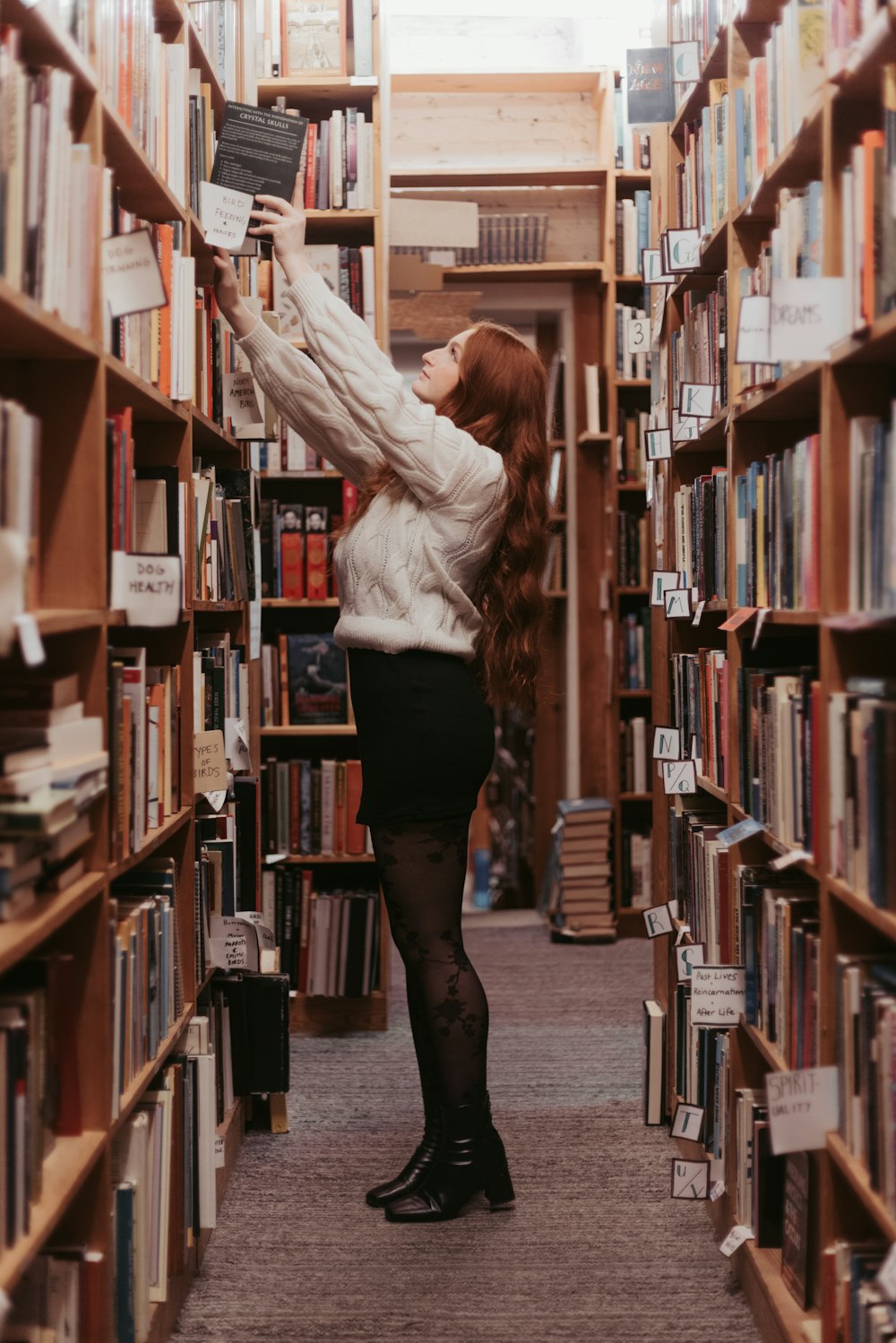 a woman standing in a library reading a book