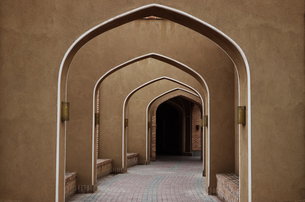 a walkway lined with arches leading to a building