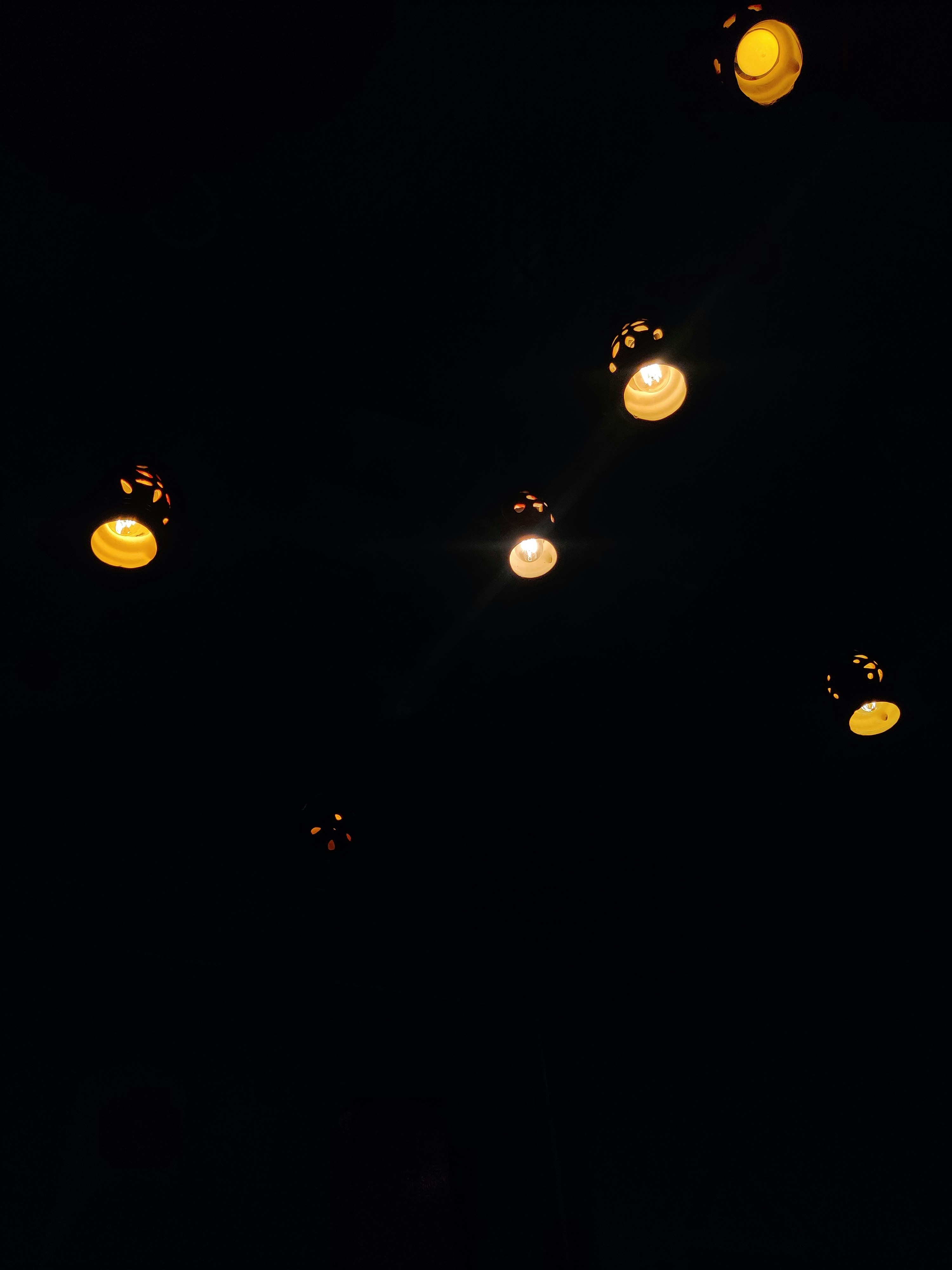 a group of lights hanging from a ceiling in the dark