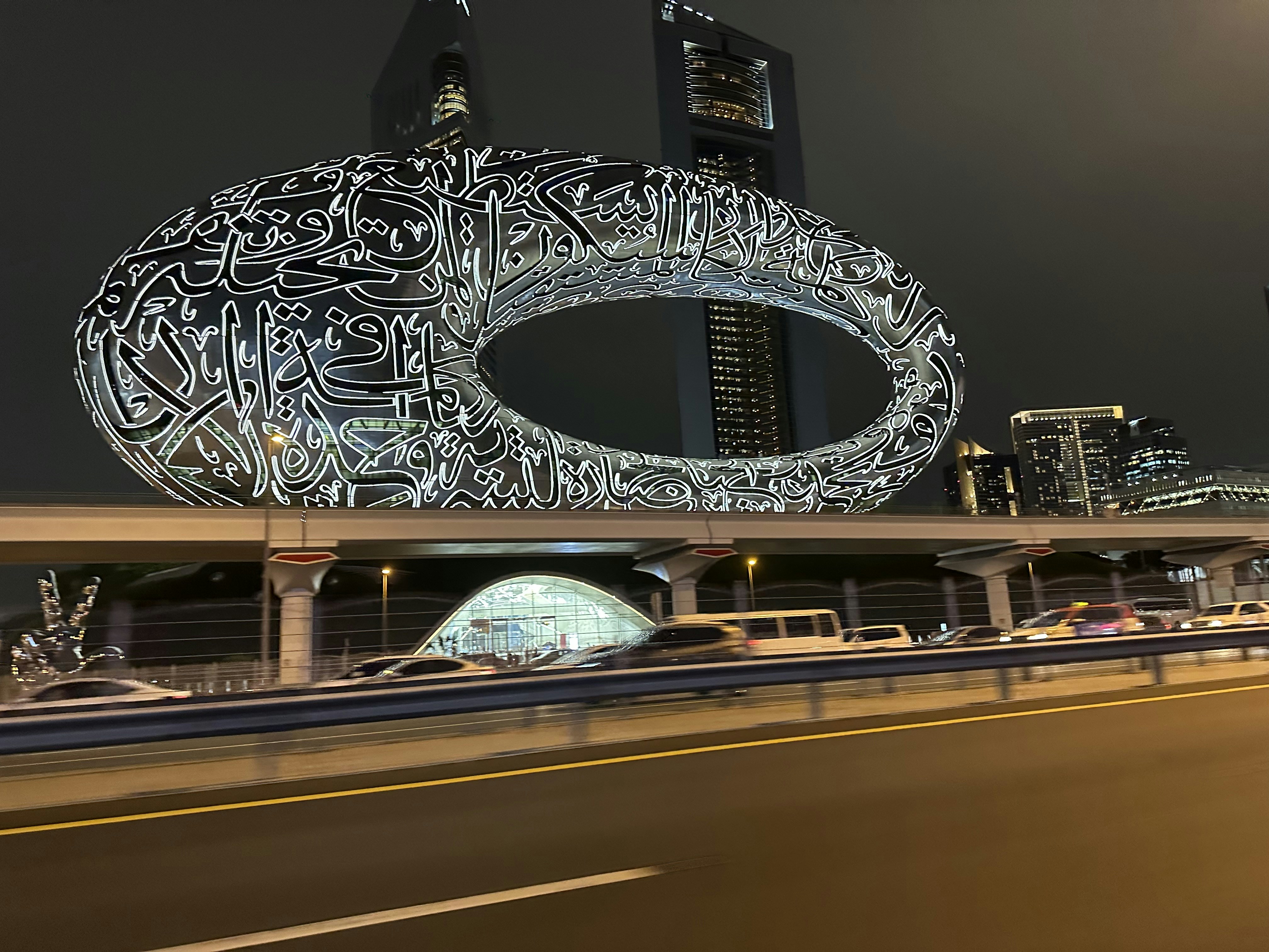 Muzej prihodnosti ikonična stavba v obliki torusa z arabsko kaligrafijo ob sončnem zahodu