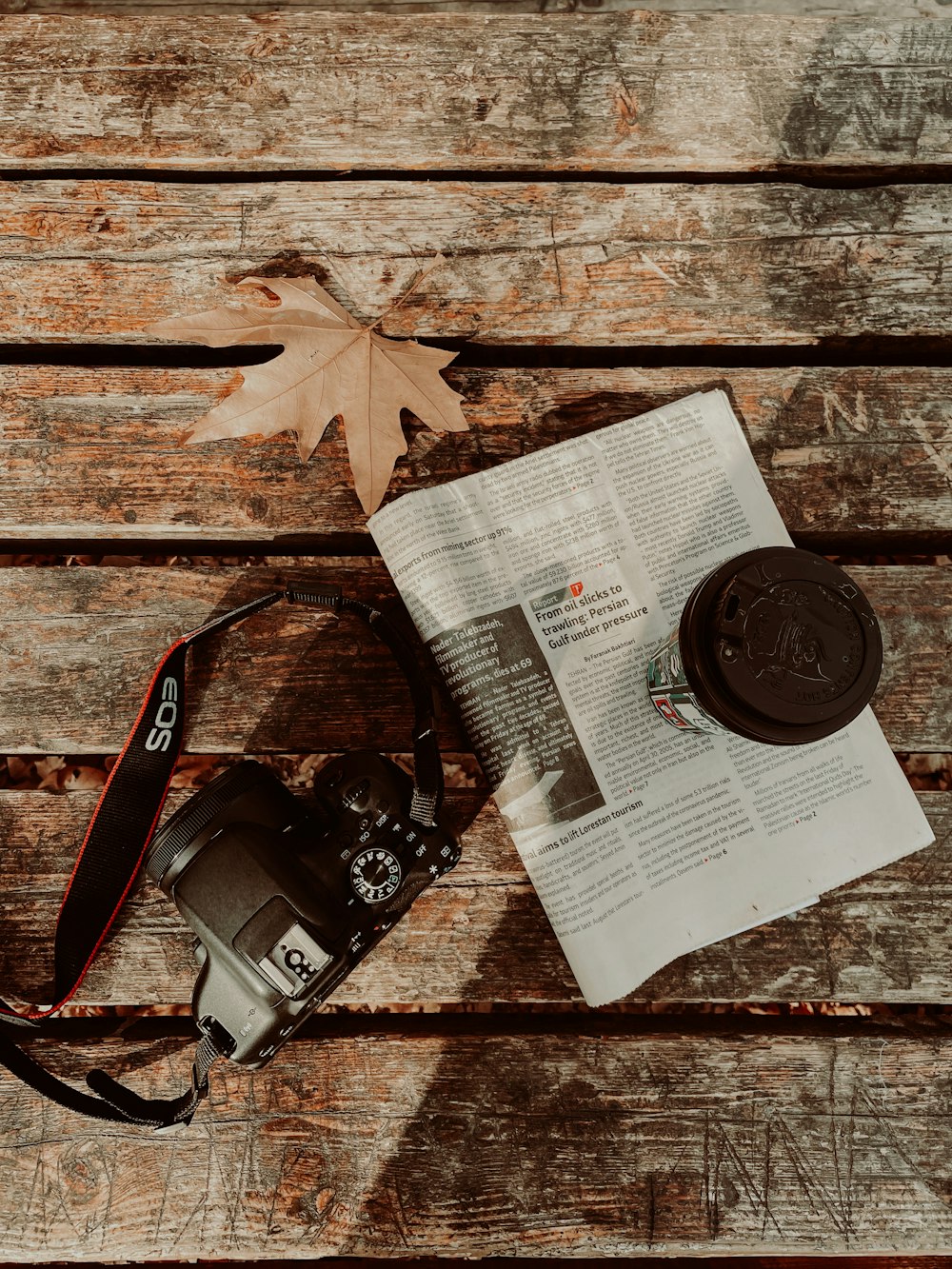 a camera sitting on top of a newspaper next to a leaf