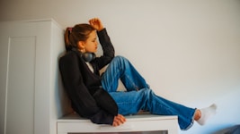 a young girl sitting on top of a microwave