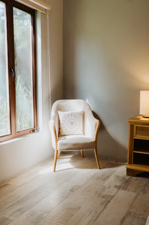 Cozy living room corner featuring a warm-toned armchair and wooden side table bathed in soft natural light.