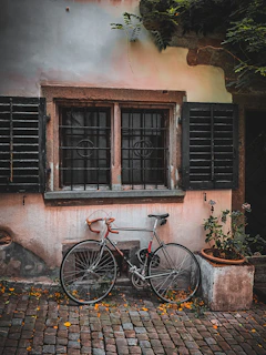 A sleek vintage city bike with a leather saddle parked against a cobblestone wall in Düsseldorf