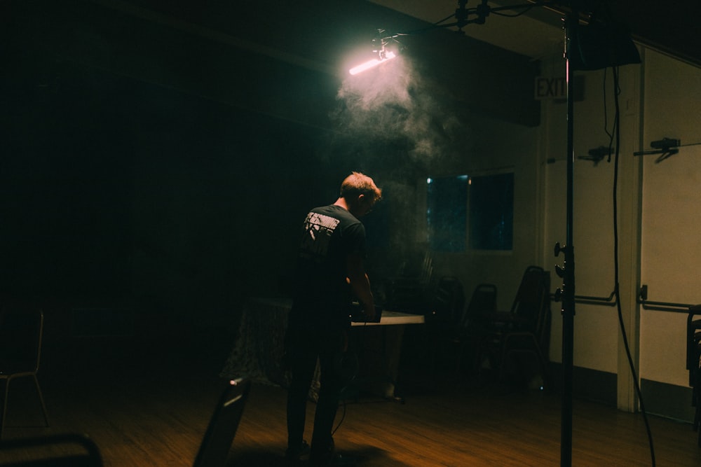 a man standing in a dark room in front of a light