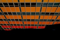 A creative grid layout featuring fragmented glimpses of faces and hands, unified by high contrast and burnt orange details.