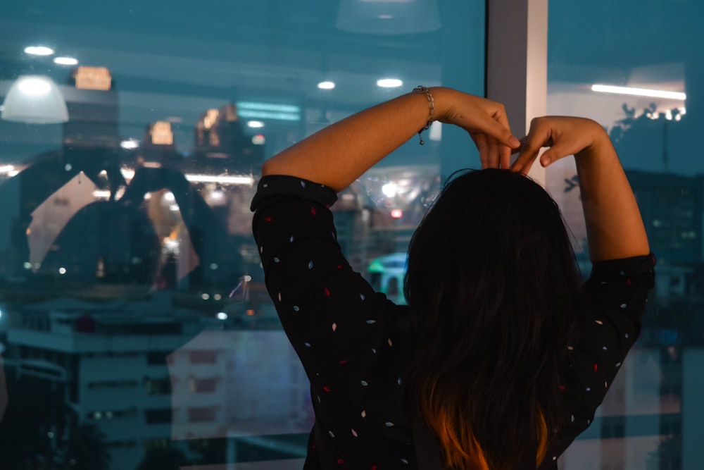 Una mujer mirando por la ventana a una ciudad por la noche