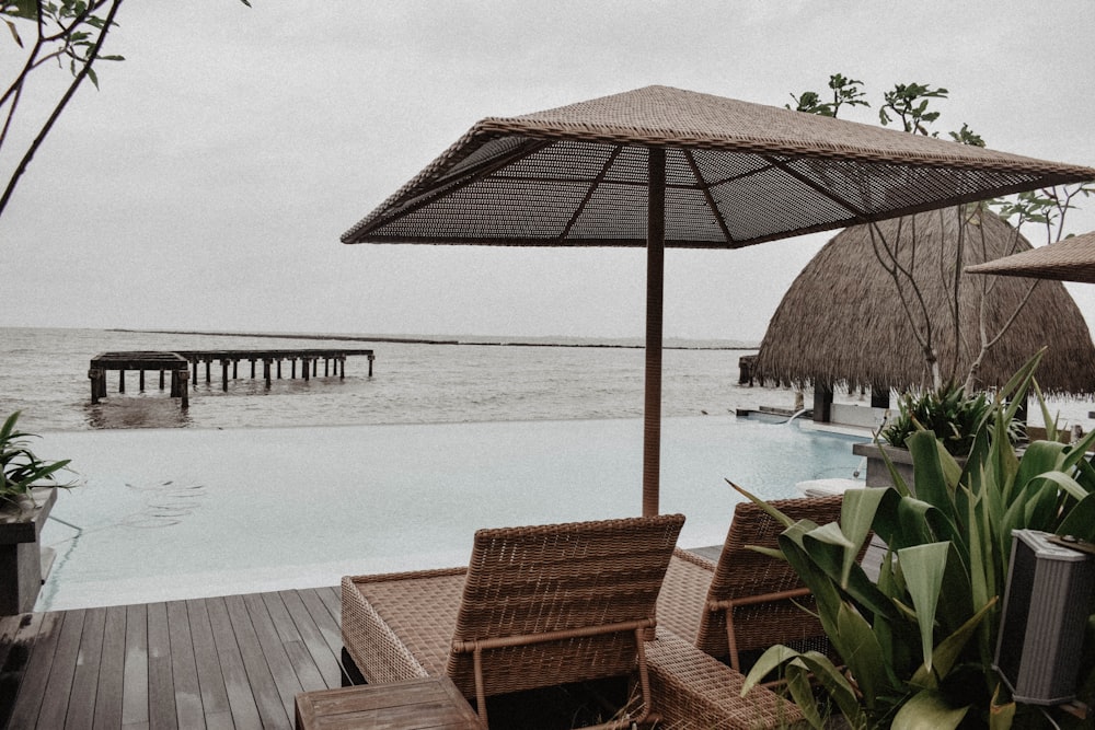 a couple of chairs sitting under an umbrella next to a pool