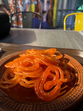 Golden jalebi spirals soaking in syrup on a bright plate