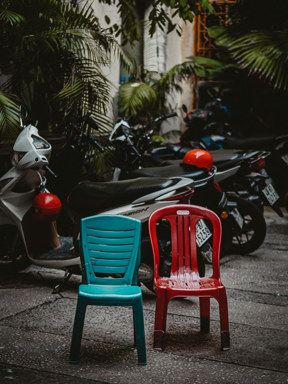 a red and a blue chair sitting on a sidewalk