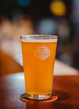 a glass of beer sitting on top of a wooden table