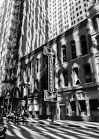 A black and white photo of an old city street with dramatic shadows.